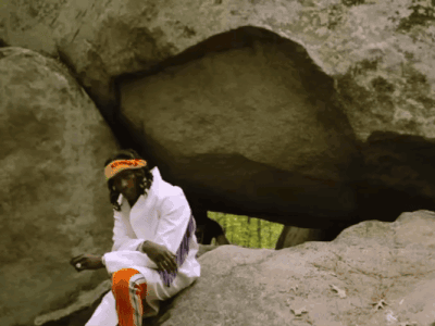 A Man Sitting On A Rock With A Headband That Says ' I Am A Native American ' On It GIF