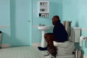 A Man Sitting On A Toilet In A Bathroom GIF