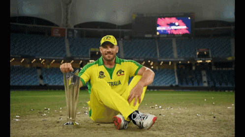 A Man Sitting On The Ground With A Trophy That Says Australia GIF