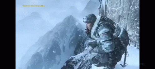 A Man Sitting On Top Of A Snow Covered Mountain Looking Out GIF