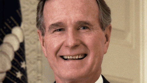A Man Smiles In Front Of A Flag That Says United States Of America GIF