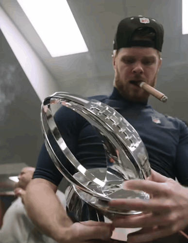 a man smoking a cigar while holding a trophy in his hands