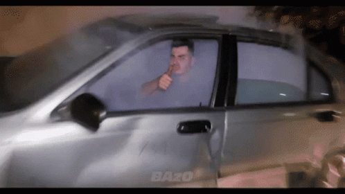 A Man Smoking A Cigarette In A Car With The Word Bazo On The Side GIF