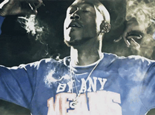 A Man Smoking A Cigarette Wearing A Shirt That Says By Any Means GIF