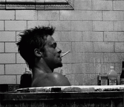 A Man Smoking A Cigarette While Taking A Bath In A Bathtub Surrounded By Bottles Of Medicine GIF