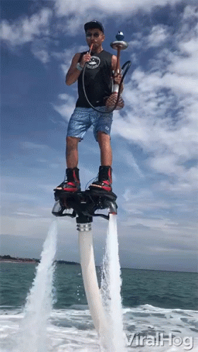 A Man Smoking A Hookah While Standing On A Water Jet Board GIF