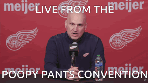 A Man Speaking Into A Microphone In Front Of A Meijer Logo GIF