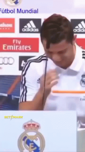 A Man Speaking Into A Microphone With A Fly Emirates Logo In The Background GIF