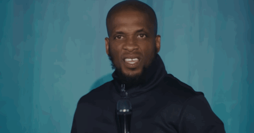 A Man Speaking Into A Microphone With His Mouth Open GIF
