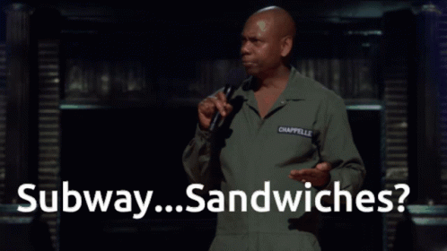 A Man Speaking Into A Microphone With The Words " Subway Sandwiches " Behind Him GIF