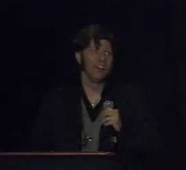 A Man Speaking Into A Microphone With The Words Voidmerch Written Below Him GIF