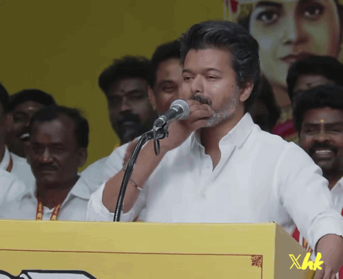A Man Speaking Into A Microphone With Xhk Written On A Yellow Box GIF