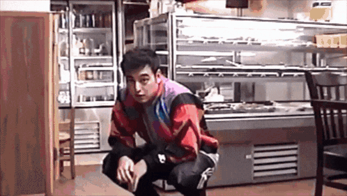 A Man Squatting Down In Front Of A Display Case GIF