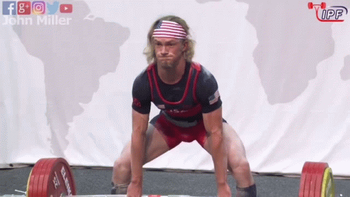 A Man Squatting Down With A Barbell In Front Of A Sign That Says John Miller GIF