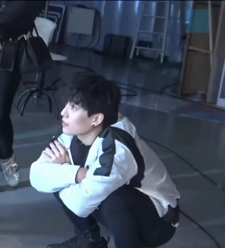 A Man Squatting Down With His Hands Folded GIF