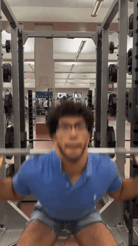 A Man Squatting With A Barbell In A Gym With A Star On The Wall GIF