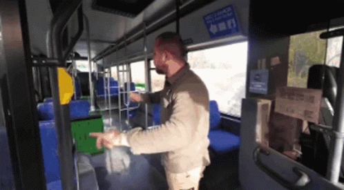 A Man Standing In A Bus With A Sign On The Wall That Says " Recycle Here " GIF