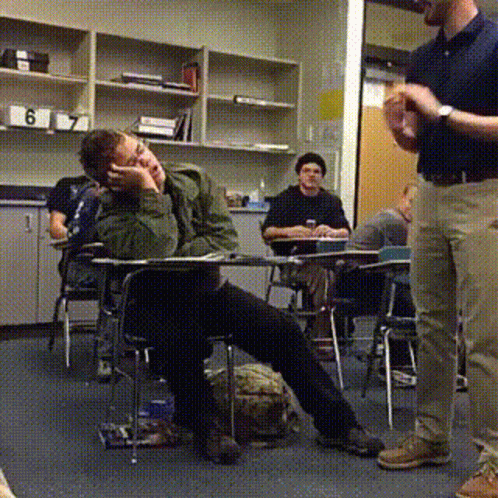 A Man Standing In A Classroom With The Number 6 On The Shelf GIF