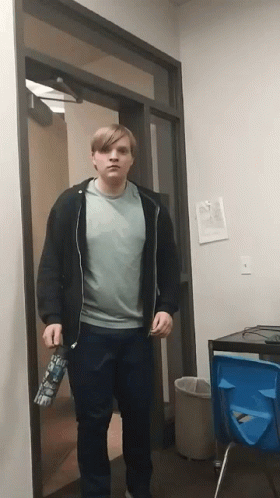 A Man Standing In A Doorway Holding A Water Bottle That Says ' I 'M Sorry ' On It GIF