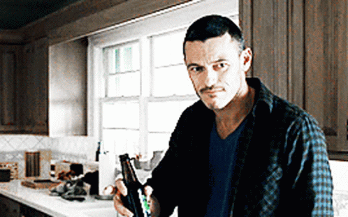 A Man Standing In A Kitchen Holding A Bottle GIF