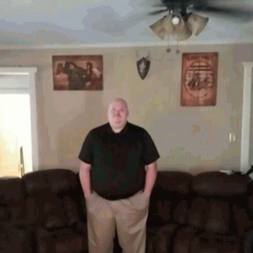 A Man Standing In A Living Room With His Hands In His Pockets . GIF