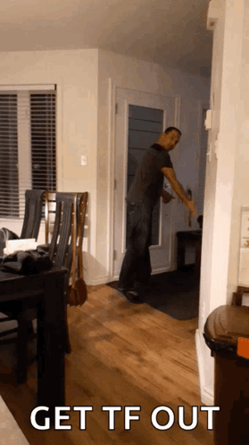 A Man Standing In A Living Room With The Words Get Tf Out GIF