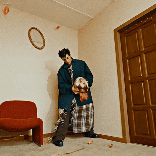 A Man Standing In A Room With A Red Chair And A Mirror On The Wall GIF