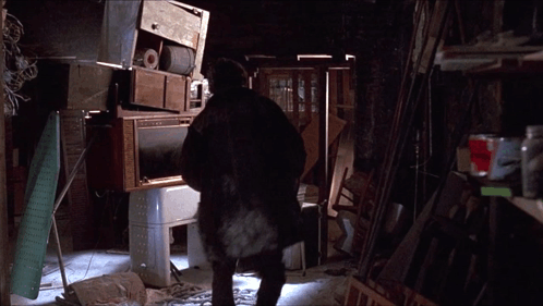 A Man Standing In A Room With A Stack Of Appliances GIF
