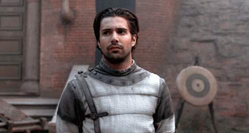 A Man Standing In Front Of A Brick Wall With A Target In The Foreground GIF