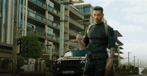 A Man Standing In Front Of A Building That Says New Motor GIF