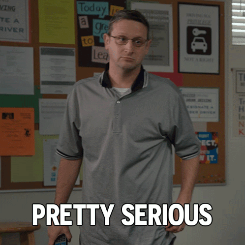 A Man Standing In Front Of A Bulletin Board With Pretty Serious Written On It GIF