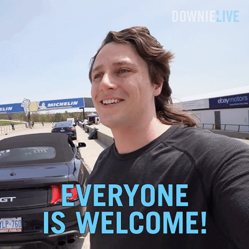 A Man Standing In Front Of A Car With The Words Everyone Is Welcome GIF