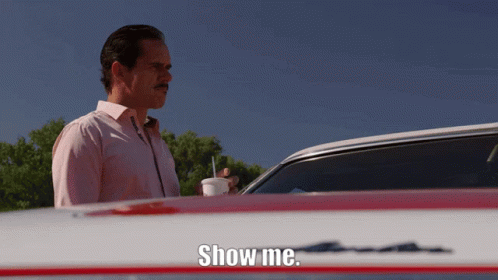 A Man Standing In Front Of A Car With The Words Show Me On The Hood GIF
