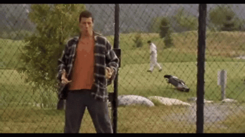 A Man Standing In Front Of A Chain Link Fence GIF