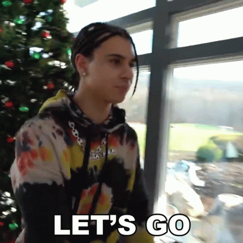 A Man Standing In Front Of A Christmas Tree With The Words Let 'S Go Below Him GIF