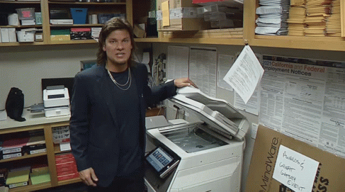 A Man Standing In Front Of A Copy Machine With A Sign On It That Says Mindware GIF