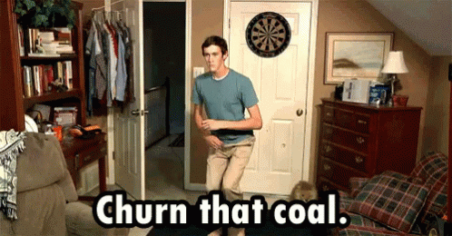 A Man Standing In Front Of A Dart Board With The Words Churn That Coal Written Below Him GIF