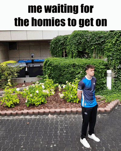 A Man Standing In Front Of A Garden With The Words " Me Waiting For The Homies To Get On " Above Him GIF