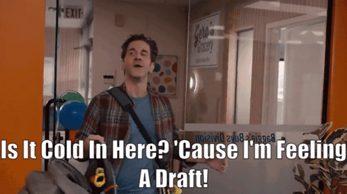 A Man Standing In Front Of A Glass Door With The Words " Is It Cold In Here " Written On It GIF