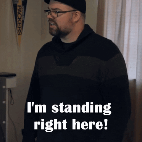 A Man Standing In Front Of A Green Bay Packers Banner That Says I 'M Standing Right Here GIF