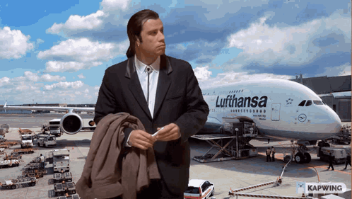 A Man Standing In Front Of A Lufthansa Plane GIF