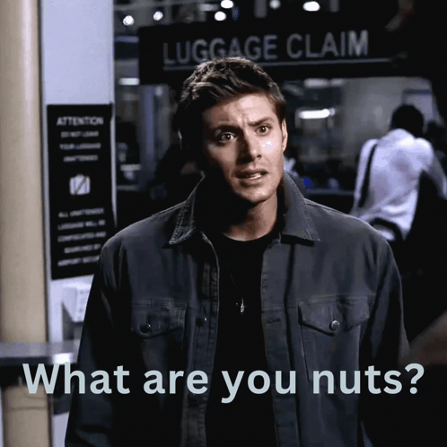 A Man Standing In Front Of A Luggage Claim Sign GIF