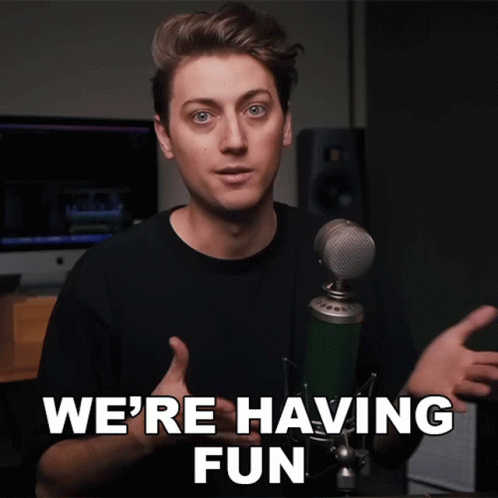 a man standing in front of a microphone with the words we 're having fun above him