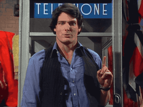 A Man Standing In Front Of A Phone Booth That Says Telephone GIF