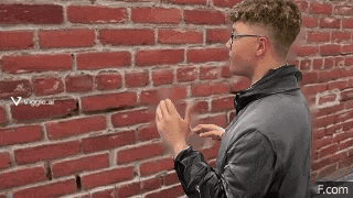 a man standing in front of a red brick wall with a if.com watermark