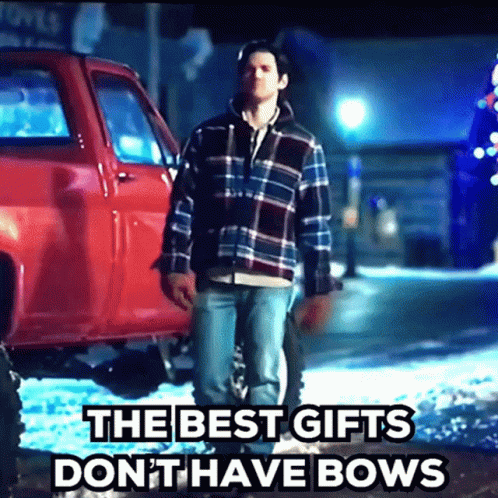 A Man Standing In Front Of A Red Truck With The Words " The Best Gifts Don T Have Bows " GIF