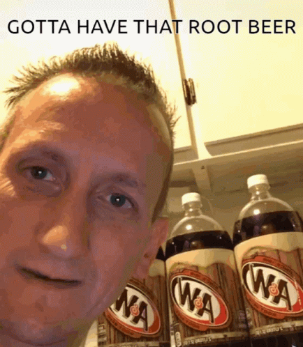 A Man Standing In Front Of A Shelf Of Root Beer GIF