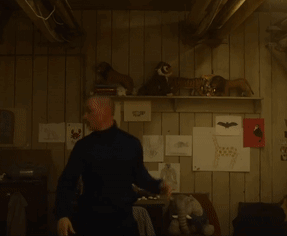 A Man Standing In Front Of A Shelf With Stuffed Animals GIF