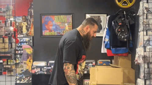 A Man Standing In Front Of A Sign That Says Guns N Roses On It GIF