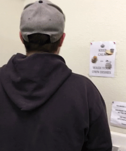 A Man Standing In Front Of A Sign That Says Keep Calm GIF
